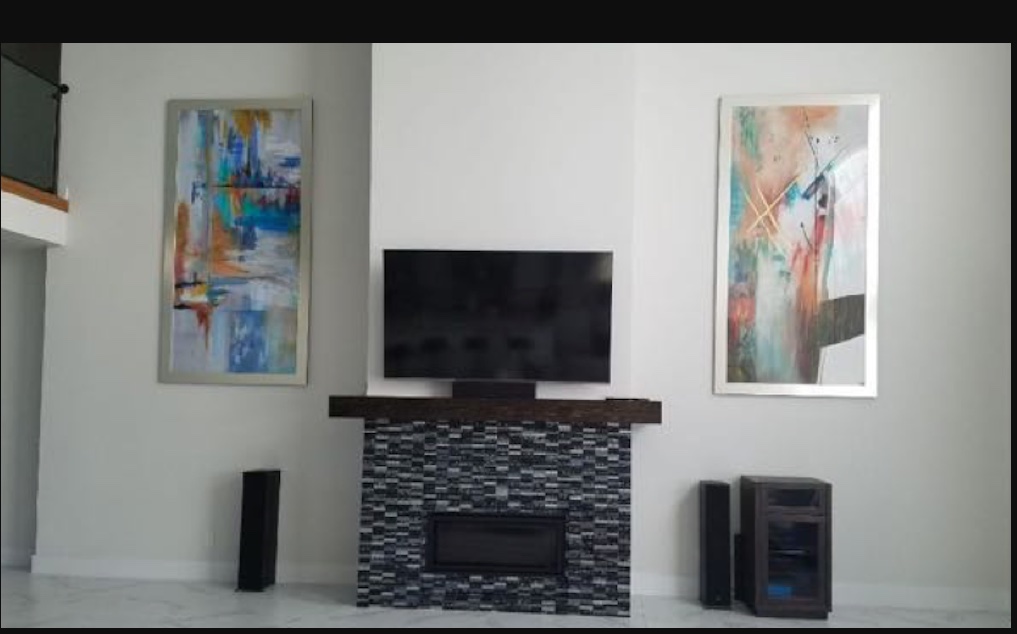 Two framed abstract paintings installed above a fireplace in a client's home