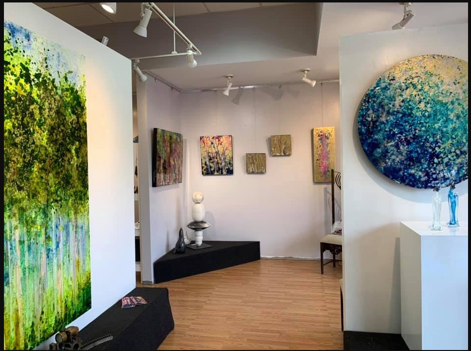 Interior of Perimeter Art Gallery showing framed abstract paintings on white walls with track lighting
